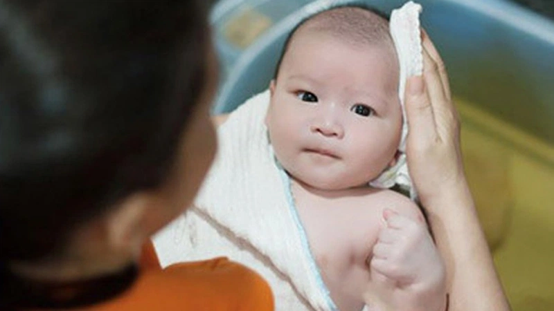 Khi con bị rôm sảy, mẹ vẫn tắm cho bé nhưng tắm bằng nước ấm, và dùng khăn mềm để lau người cho con