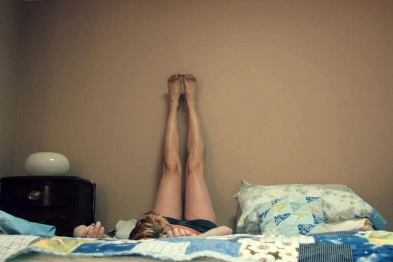 Bài tập giảm mỡ bụng trên giường: nằm gác chân lên tường