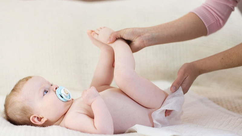 Tháo bỉm cũ và vệ sinh sạch sẽ cho bé