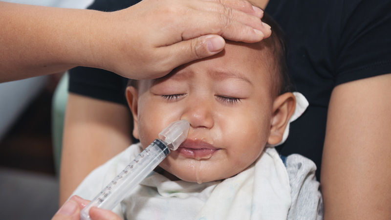 Khi trẻ nghẹt mũi, có thể sử dụng nước muối sinh lý để nhỏ hoặc vệ sinh mũi