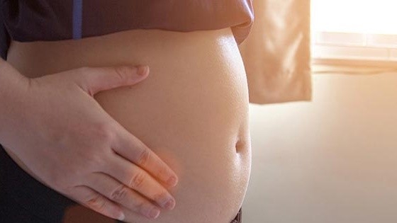 When sitting, does the belly show any visible indentation during the first month of pregnancy?